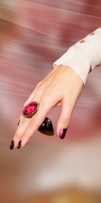 Mano con anillo rojo y uñas pintadas.